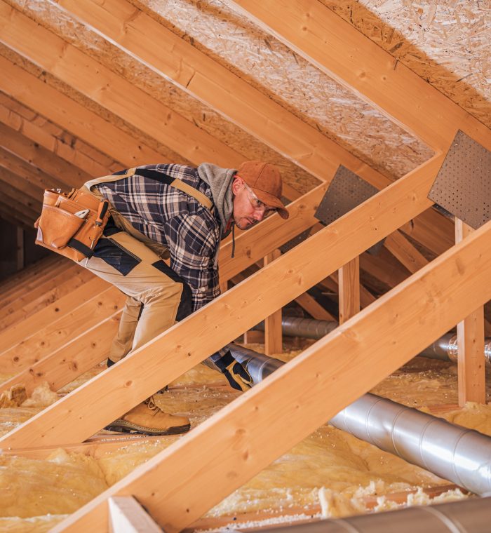 Male Contractor Installs Metal Pipe System In Attic.