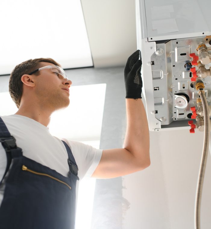 Professional plumber checking a boiler and pipes, boiler service concept